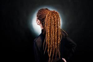 sesión de estudio de una chica de negro con rastas en fondo negro con nimbus. foto