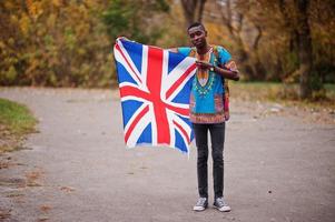 hombre africano en camisa tradicional de áfrica en el parque de otoño con bandera de gran bretaña. foto