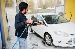 hombre del sur de asia o hombre indio lavando su transporte blanco en el lavado de autos. foto