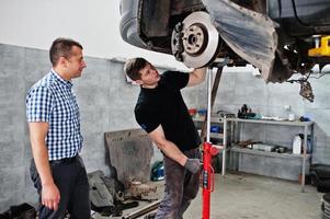 Car repair and maintenance theme. Mechanic in uniform and manager working in auto service. photo