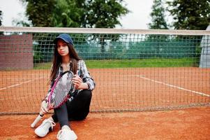 Young sporty girl player with tennis racket on tennis court. photo