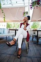 African american girl wear in glasses with mobile phone sitting at outdoor caffe. photo