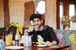 Beard asian man in casual wear sitting indoor cafe and drink coffee. photo