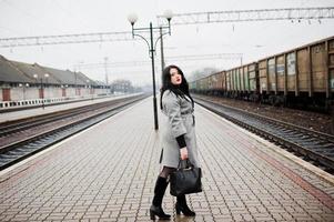 Brunette girl in gray coat posed in railway station. photo