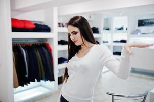 hermosa chica morena en la boutique de la tienda de ropa en ropa casual. foto