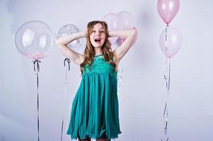 Happy girl in green turqoise dress with colored balloons isolated on white. Celebrating birthday theme. photo