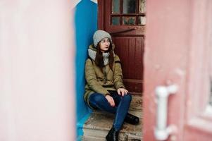 Portrait of brunette girl in gray scarf and hat, glasses against entrance. photo