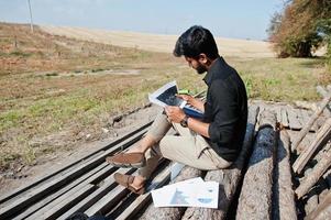 South asian agronomist farmer looking at diagram papers on farm. Agriculture production concept. photo