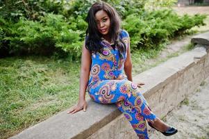 African american girl in coloured clothes sitting outdoor. Fashionable black woman. photo