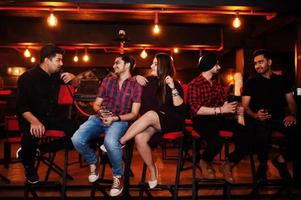 Group of indian friends sitting at lounge bar, smoke hookah and having rest. photo