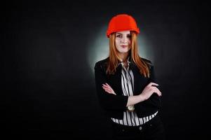 Engineer woman in orange protect helmet on studio black background. photo