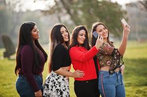 Group of four happy and pretty latino girls from Ecuador posed at street and making selfie on phone. photo
