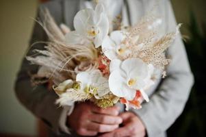 Groom holding beautiful tender wedding bouquet. photo