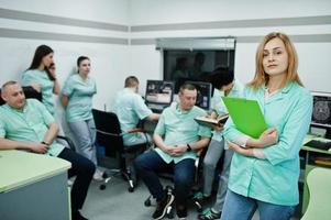 Medical theme .Portrait of female doctor with clipboard against group of doctors meeting in the mri office at diagnostic center in hospital. photo