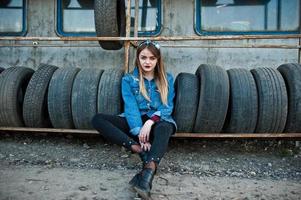 Young hipster girl in jeans jacket and head scarf at tire fitting zone. photo