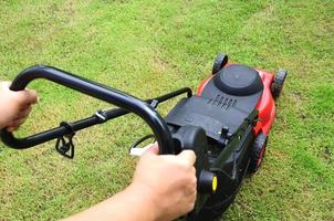 Gardener mowing the lawn in the garden. photo