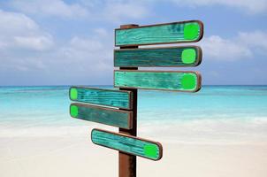 Wood signs for travel directions on the beach with sea and blue sky background. photo