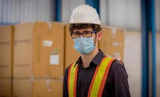 Factory engineer under inspection and checking quality production process on face mask manufacture  station by  wearing casual uniform and safety helmet in factory plantation. photo