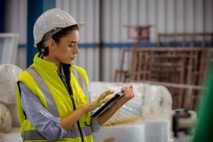 Factory engineer under inspection and checking quality production process on face mask manufacture  station by  wearing casual uniform and safety helmet in factory plantation. photo