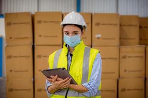 Factory engineer under inspection and checking quality production process on face mask manufacture  station by  wearing casual uniform and safety helmet in factory plantation. photo