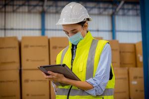 ingeniero de fábrica bajo inspección y verificación del proceso de producción de calidad en la estación de fabricación de máscaras faciales usando uniforme informal y casco de seguridad en la plantación de fábrica. foto