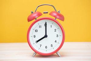 vintage retro alarm clock eight minutes to twelve time o'clock on table wood with yellow background. photo