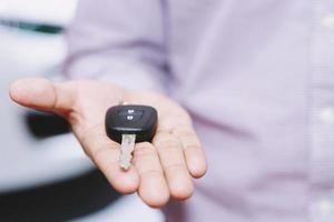 Car key, businessman handing over gives the car key to the other man on car background. photo