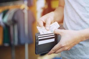 Man standing holding black wallet full of money photo