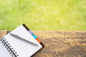 blank notebook with pen and pencil on wooden table, business concept photo
