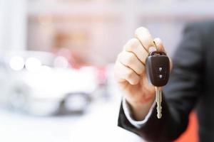Male holding car keys with car on background photo