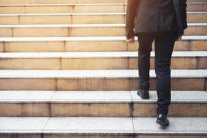 Ambitious businessman going up staircase. Back turned. photo