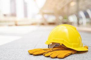 sombrero de casco de seguridad duro amarillo en el proyecto en el edificio del sitio de construcción en el piso de concreto en la ciudad con luz solar. casco para obrero como ingeniero o trabajador. concepto de seguridad primero. foto