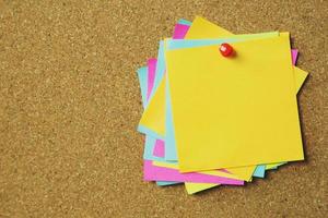 collection of colorful variety post it. paper note reminder sticky notes pin on cork bulletin board. empty space for text. photo