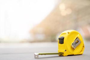 yellow tape measure background in the project at construction site building on concrete floor on city with sunlight. tool for workman as engineer or worker. photo