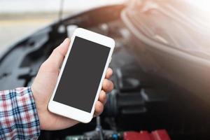 close up young business man hand using a mobile smart phone call a car mechanic ask for help assistance because car broken on the roadside. blank if empty screen. photo