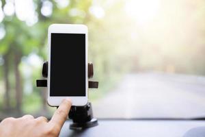 close up hand holding using mobile smart phone with black screen in car console front windshield holder stick. insert map gps navigation travel on the in the background of the dashboard. copy space. photo