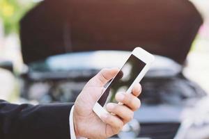 cierre la mano femenina usando un teléfono inteligente móvil llame a un mecánico de automóviles pida ayuda porque el automóvil se rompió en la carretera. en blanco de la pantalla vacía. foto