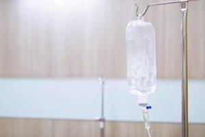 Iv saline bag infusion set and bottle on a pole. fluid intravenous drop saline drip slow hospital room or clinic. medical concept,treatment emergency shock. injection drug infusion care chemotherapy photo