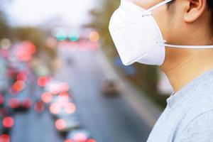 joven apuesto caminando por el mercado nocturno en taipei con mochila y usando una máscara de contaminación facial para protegerse del coronavirus. foto