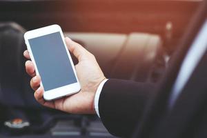 close up businessman hand using a mobile smart phone call a car photo