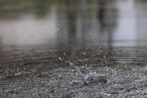 gotas de lluvia en el agua pesada sobre sombra de asfalto de sombra negra y reflejo del cielo oscuro en la ciudad. alto contraste durante el otoño foto