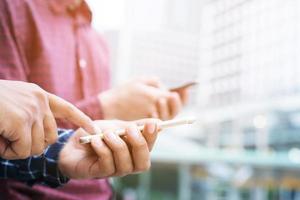 reunión de grupo de empresarios, intercambio de llamadas, número de teléfono inteligente móvil y envío de mensajes en la oficina al aire libre. compartir conectar bluetooth o primer plano de manos personas hombre dos. distanciamiento social. nueva normalidad. foto