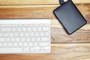 Modern aluminum computer keyboard of a laptop and Hard disk on the desk office wood. technology Electronic Devices. Top view. Hdd photo