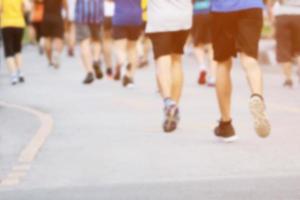 grupo de fotos borrosas multitud de personas. Pies de corredor de atleta haciendo ejercicio en la pista de carreras en la calle cerca de la orilla en el parque público. concepto de bienestar de entrenamiento de trote de fitness.