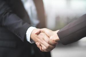 Two businessmen shake hands on the background of empty modern office, signing of a contract concept, photo