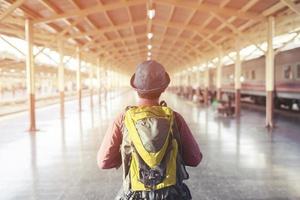 The passengers are stand waiting for the Station platform. Young asian man traveler with backpack looking waiting for train. the tourist travel Get ready for departure concept. photo