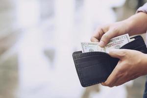 Businessman Person holding an wallet in the hands of an man take money out of pocket. photo