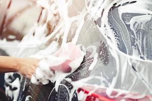 people man holding hand pink sponge for washing car. cleaning wheel tire. Concept car wash clean. photo