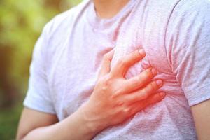 Man having chest pain - heart attack causes the body to shock disease on sofa in the living room. or have colic acid flows back to the chest. Health care concept. photo