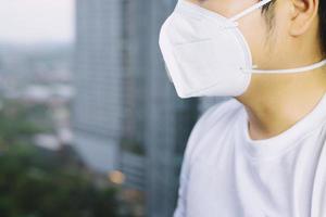 joven apuesto caminando por el mercado nocturno en taipei con mochila y usando una máscara de contaminación facial para protegerse del coronavirus. foto